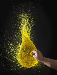 Close-up of hand holding water splashing against black background