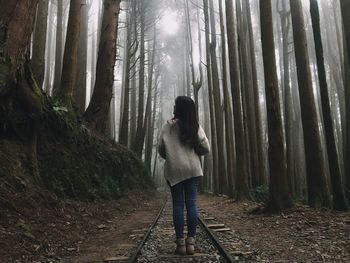 Woman standing by trees in forest