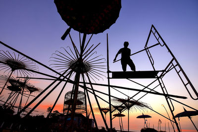 Low angle view of silhouette person on structure against orange sky