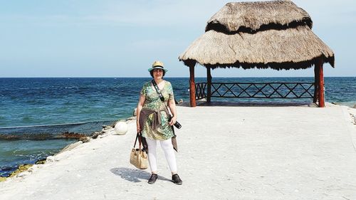 Woman with umbrella on beach against sky