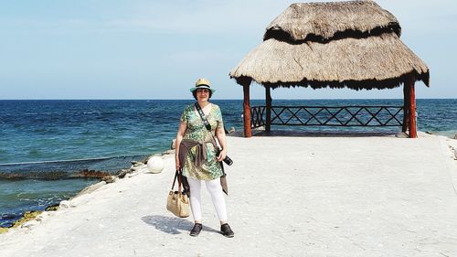 Portrait of woman standing at beach against sky