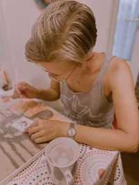 Midsection of woman holding coffee cup on table at home