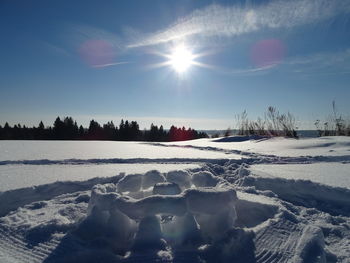 Scenic view of snow covered field against bright sun