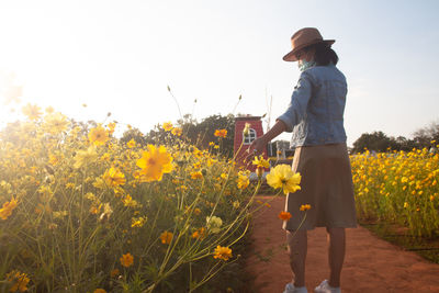 Rear view of woman walking on field against sky