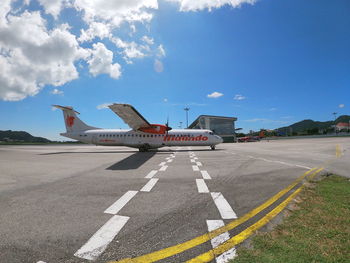 Airplane on airport runway against sky