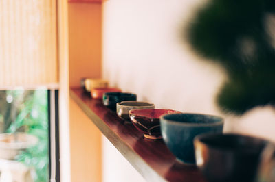 Bowls on wooden plank against wall
