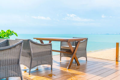 Deck chairs by swimming pool at beach against sky