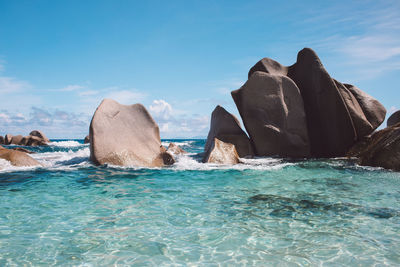 Rock formations in sea against blue sky