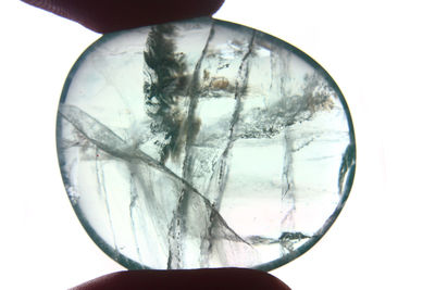 Close-up of hand holding glass against white background