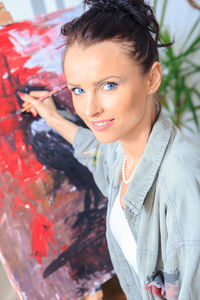 Portrait of smiling artist painting while sitting at home