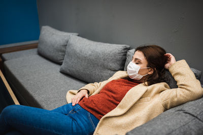 Midsection of woman lying on sofa at home