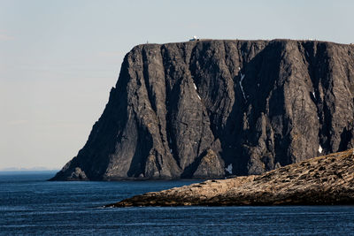 Rock formations by sea against clear sky