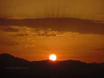Scenic view of silhouette mountains against orange sky