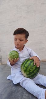 Boy holding watermelon sitting on floor