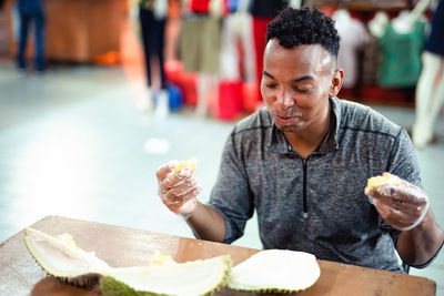 Man eating durian while sitting at table