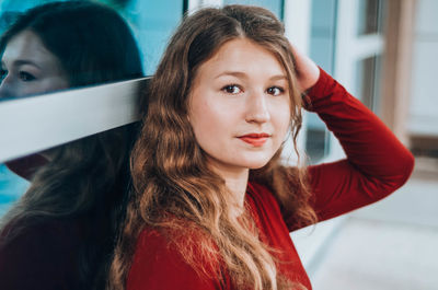 Close-up of beautiful girl sitting with hand in hair indoors