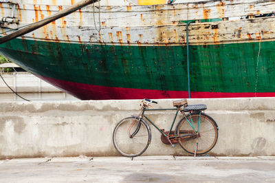 Bicycle leaning against wall by boat