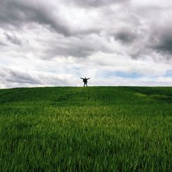 Scenic view of grassy field against cloudy sky