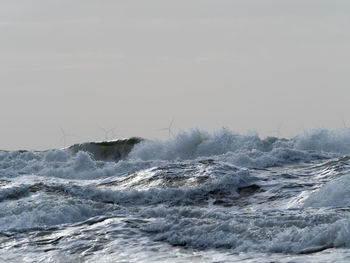 Waves splashing in sea against clear sky