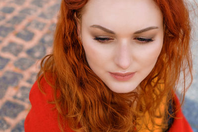 Close-up portrait young caucasian woman with red curly hair in a red coat
