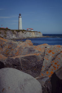 Lighthouse by sea against sky