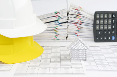 Close-up of hardhat by paperwork stacked on table