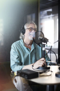 Mature man sitting and hosting podcast or radio show or podcast