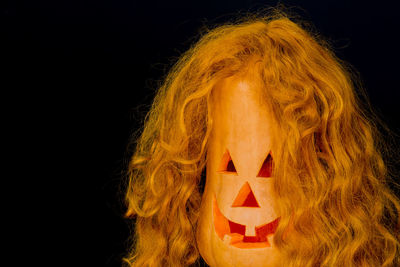 Close-up of jack o lantern with wig and sunglasses against black background
