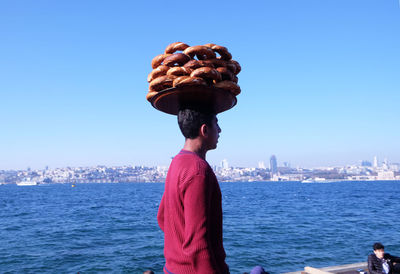 Man with umbrella in city against clear sky