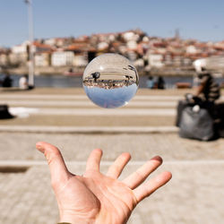 Close-up of hand holding crystal ball in city