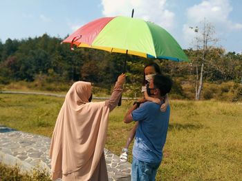 Rear view of woman with umbrella standing on field