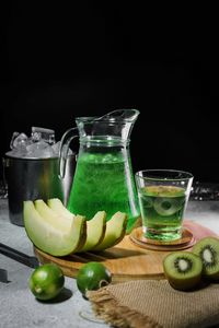 Fruits in glass on table against black background