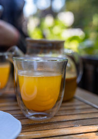 Hot spicy sea buckthorn tea in glass teapot with mint, orange and honey, wooden table in cafe. 