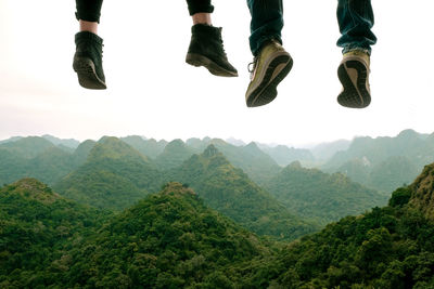 Low section of people by mountains against sky