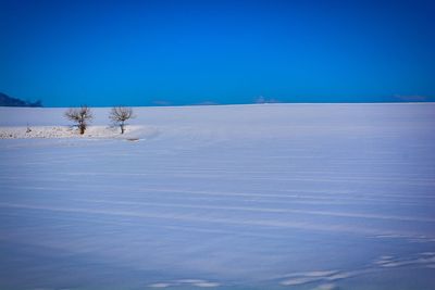 Scenic view of frozen lake against clear blue sky