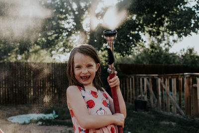 Young girl playing outside with spraying hose