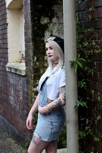 Young woman smiling while standing against brick wall