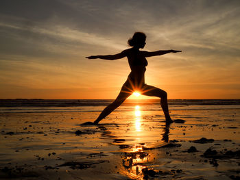 Silhouette man standing on beach against sky during sunset