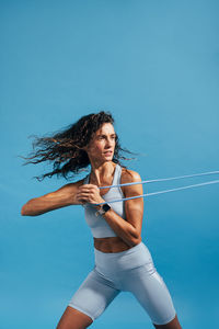 Woman exercising against blue background