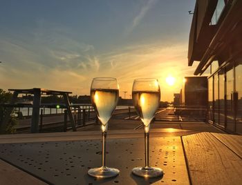 Wine glass on table against sky during sunset