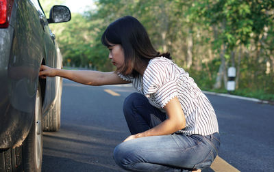 Side view of young woman sitting on car