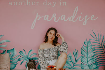 Portrait of young woman standing against wall