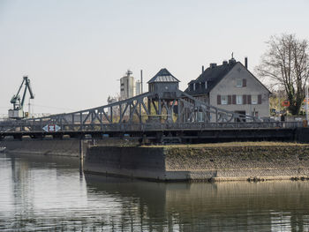 Bridge over river by buildings against clear sky