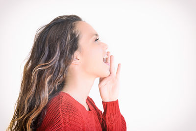 Close-up of smiling young woman against white background