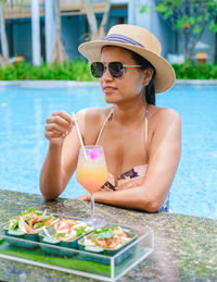 Young woman drinking water in pool