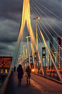 Rear view of people walking on bridge at night