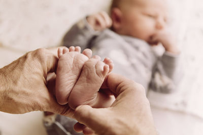 Feet of newborn baby boy being held by father’s hands