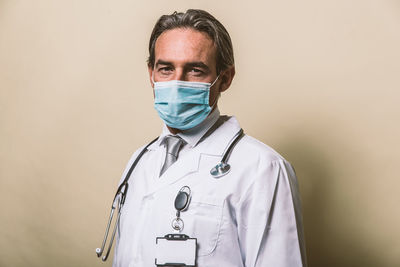 Close-up portrait of doctor wearing mask against colored background