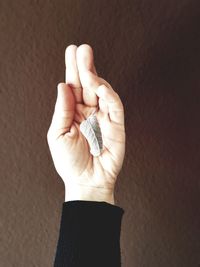 Close-up of person holding hands against wall