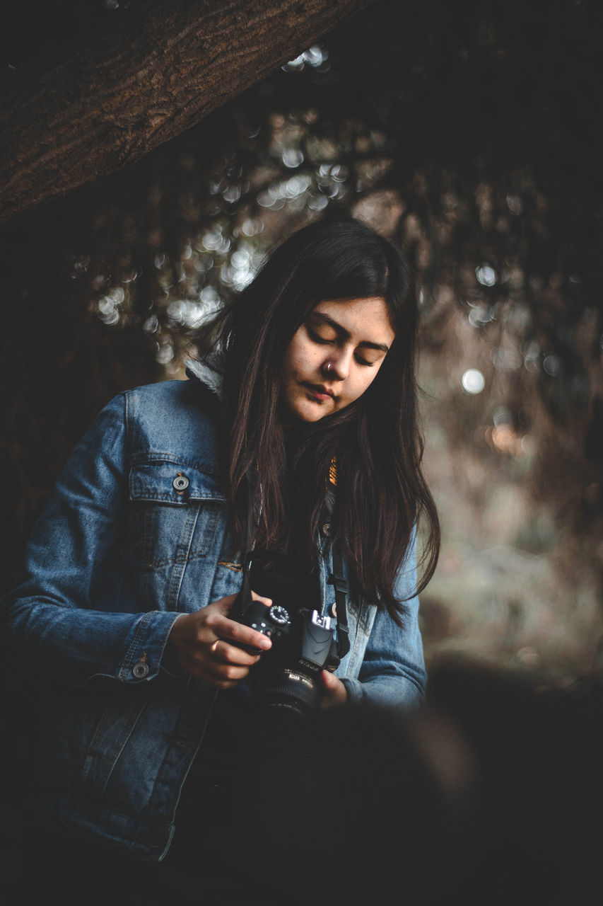 one person, hair, real people, long hair, young adult, technology, leisure activity, lifestyles, hairstyle, casual clothing, holding, young women, communication, front view, activity, mobile phone, photography themes, telephone, tree, beautiful woman, teenager